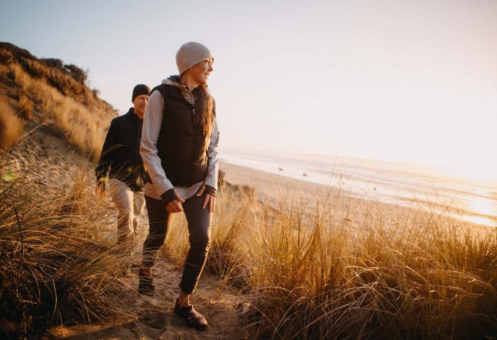 Couple walking on Woolacombe beach during Autumn holiday in North Devon