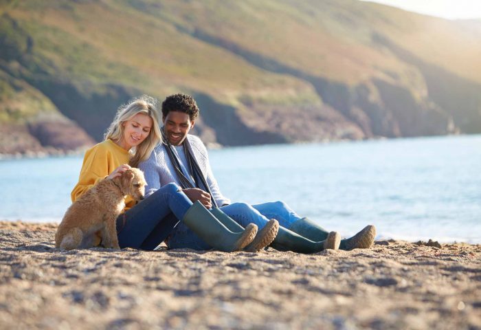 Couple with dog on beach whilst on Autumn holiday in North Devon
