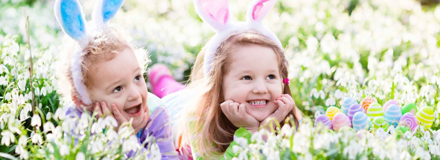 Kids on Easter egg hunt in blooming spring garden